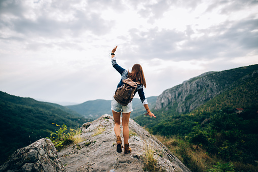 Young Hippie girl taking a walk on top of a mountain and enjoying the day. rear view